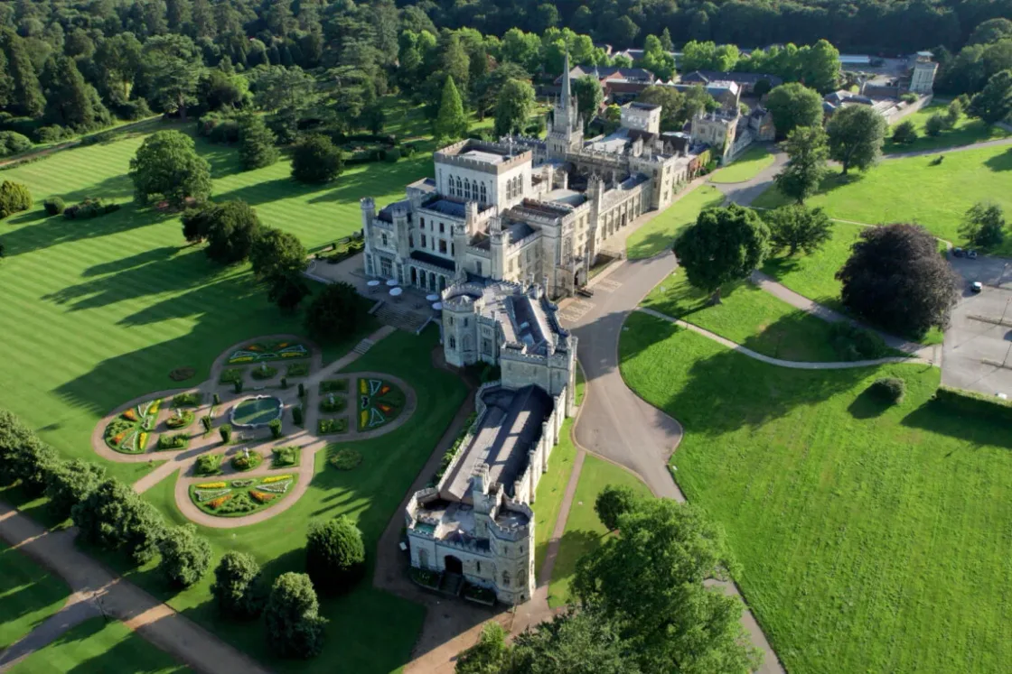 Aerial view of a country estate surrounded by formal gardens and trees.