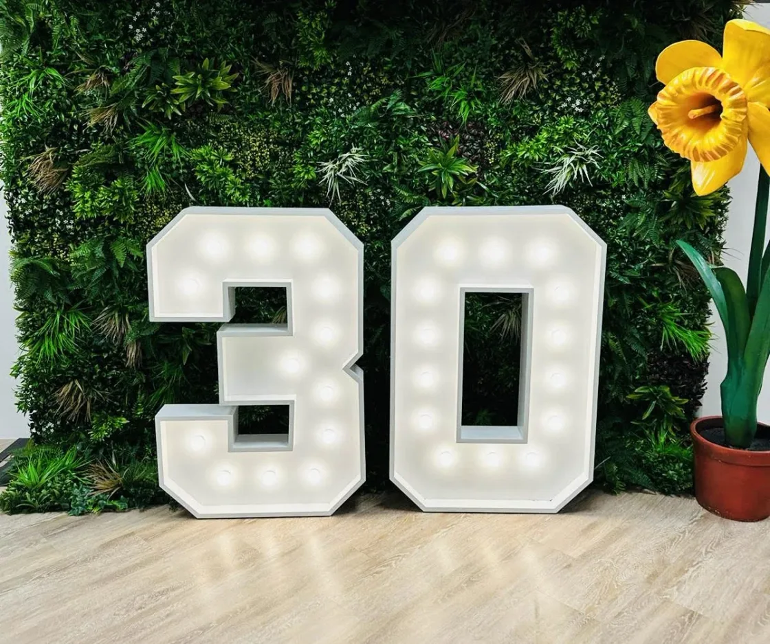 Illuminated numerals displayed against a green foliage wall.