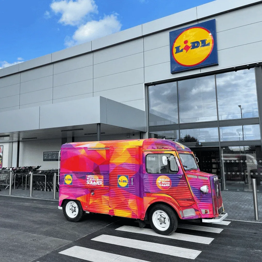 A colourful catering van parked outside a Lidl store.